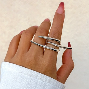 Detail of silver multi-layer overlapping cross ring worn on finger with glossy finish