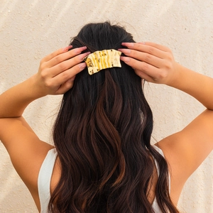 Detail shot of wavy gold hairpin with irregular hammered texture on model's hair