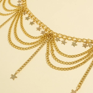 Close-up of layered gold star waist chain with metallic tassels and fringe detail