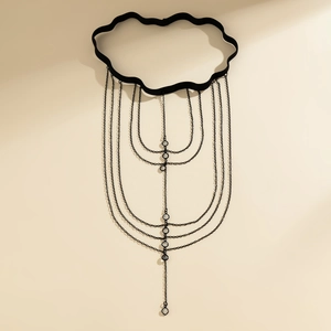 Black layered leg chain with butterfly tassels and crystals on a beige background