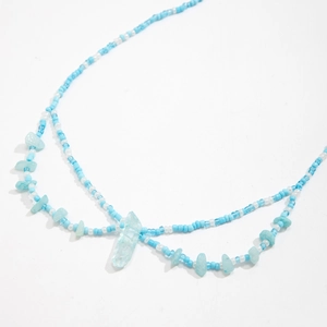 Detalle de cuentas de colores y colgante de piedra azul en cadena para la cintura