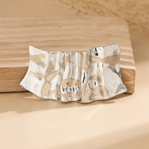 Macro shot of a minimalist irregular metallic crumpled silver hairpin on wooden board