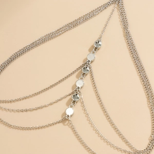 Macro detail of silver layered leg chain featuring metallic round sequin pendants