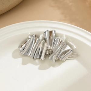 Detailed view of silver liquid metal hairpin with irregular wavy fold on ceramic tray