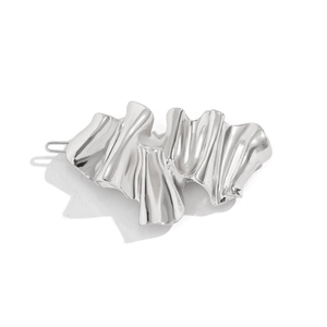 Macro shot of silver irregular wavy hairpin with polished metallic texture and back clip