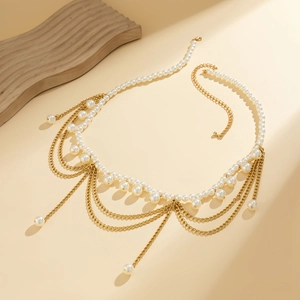 Detail of layered gold waist chain featuring elegant white pearls and fringe tassels