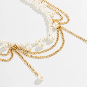 Close-up of layered gold chain and white pearl waist chain with elegant draping