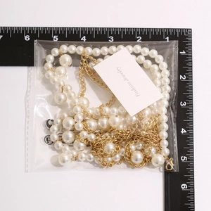 Macro detail of multi-layered gold star waist chain with pearls in its package