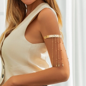 Λεπτομέρεια από χρυσό boho περιβραχιόνιο με αλυσίδες κρόσσια και μενταγιόν σε σχήμα φύλλου