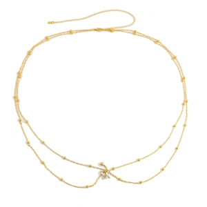 Detalle de una cadena corporal dorada con cuentas redondas y colgante de mariposa brillante