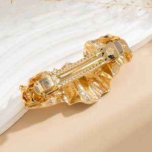 Detailed view of golden irregular wavy texture alloy hairpin with spring pressure clip