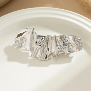 Detailed macro view of the irregular pleated texture on the shiny silver metal hairpin