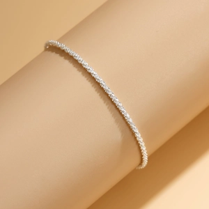 Detalle macro de una tobillera de plata brillante con una delicada textura de cadena centelleante