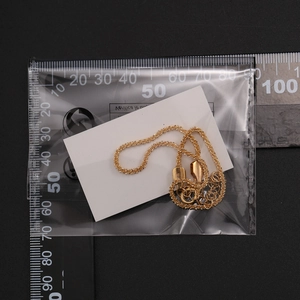 Detalle de un juego de tobilleras de cadena de oro brillante contra una regla graduada