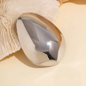 Macro shot of silver mirrored pebble hairpin on white coral texture background