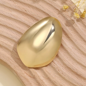 Close-up of golden irregular textured hairpin with mirror finish on wooden display