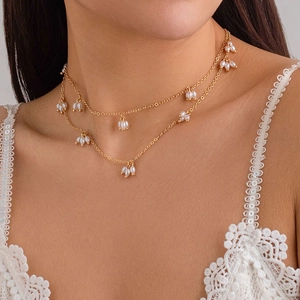 Détail d'un élégant collier double rang doré avec pendentifs perles sur la clavicule