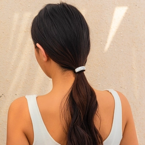 Close-up of irregular silver metal hair clip on a ponytail with a modern wrinkled texture