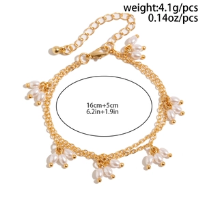 Détail d'un bracelet doré à deux couches avec grappes de perles blanches et extension