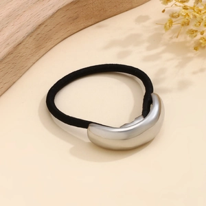 Close-up of minimalist silver metallic half-moon buckle on a black elastic hair tie