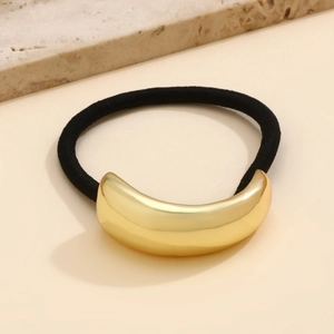 Close-up of a black elastic hair tie with a polished gold-plated curved metal accent