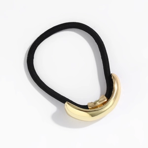 Detail shot of minimalist hair tie featuring a polished gold metal bar on black elastic