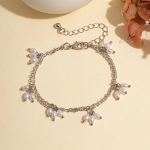 Détail du bracelet double chaîne argentée avec perles blanches et fermoir mousqueton