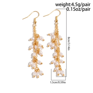 Vue détaillée de boucles d'oreilles dorées à pompons avec perles en goutte