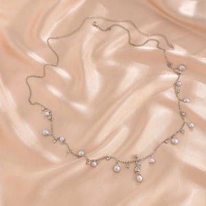 Primer plano de elegante cadena para el cuerpo plateada con perlas y dijes de cristal
