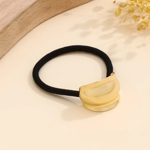 Macro detail of glossy gold curved metal buckle on a black elastic minimalist hair tie