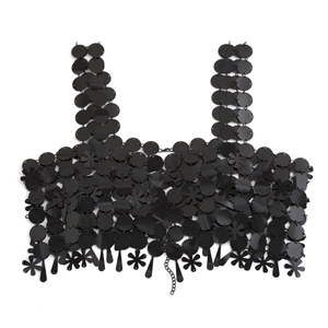 Detalle de bralette de lentejuelas negras con anillos metálicos y adornos pétalos