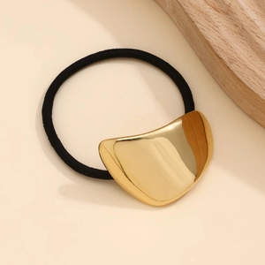 Detailed view of irregular folded golden metal hairpin on a minimalist beige background