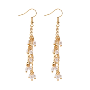 Vue détaillée de boucles d'oreilles pendantes dorées avec perles blanches sur fond blanc