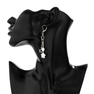Détail de boucles d'oreilles argentées avec étoiles et perle sur un mannequin noir