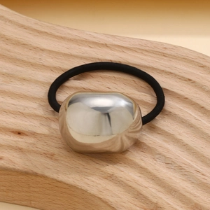 Macro shot of silver textured irregular bead on a black elastic hair tie with metallic finish