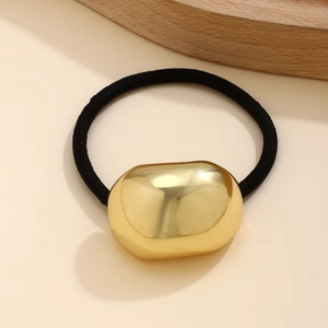 Close-up of a glossy gold irregular folded metal hairpin with a black elastic hair tie