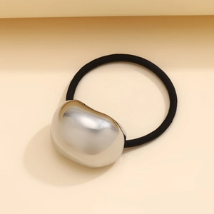 Macro view of a large mirror-polished silver metal bean on a black elastic hair tie