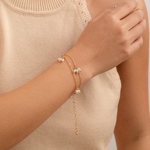 Bracelet double couche doré avec grappes de perles blanches porté par un mannequin