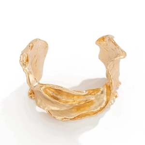 Primer plano de un brazalete ancho dorado con textura orgánica y bordes irregulares