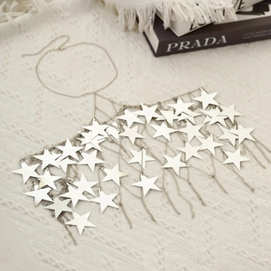 Detail showing silver star sequin body chain with tassel fringe on white knit fabric