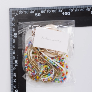 Detailopname van schelphanger en veelkleurige kralen tailleketting op een meetlatje