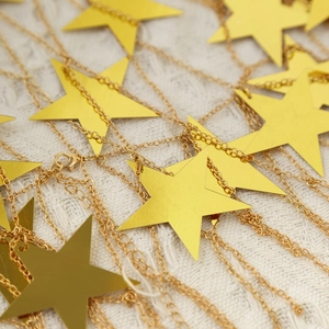 Detail of gold star pendant body chain featuring brushed metal finish and lobster clasp