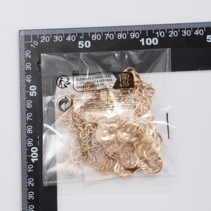 Detail view of a gold punk style waist chain with metallic heart pendants in packaging