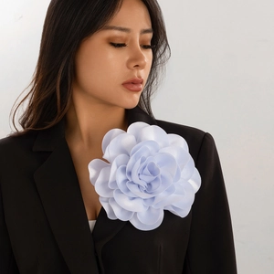Detail of a large light blue satin flower brooch worn on a dark suit lapel