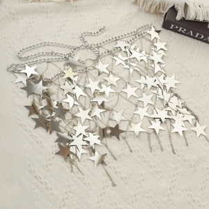 Detailed view of silver metallic star body chain on a beige knit texture background