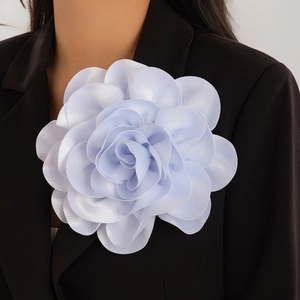 Detailed view of large light blue satin rose brooch pinned on a black blazer lapel