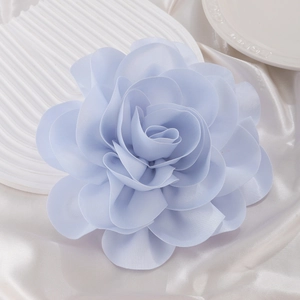 Macro detail of multi-layered light blue satin rose brooch with soft fabric petals