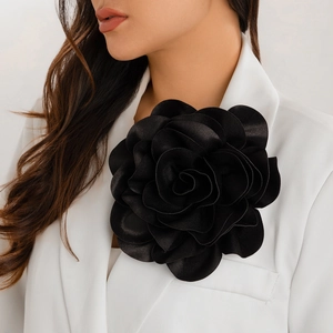 Close-up of a large black satin rose brooch pinned to a white suit jacket lapel