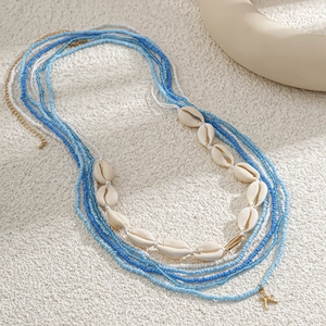 Macro shot of layered beach waist chain with blue beads, white shells and gold starfish