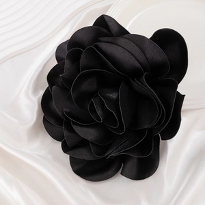 Macro shot of 3D layered black satin rose brooch showing detailed fabric texture
